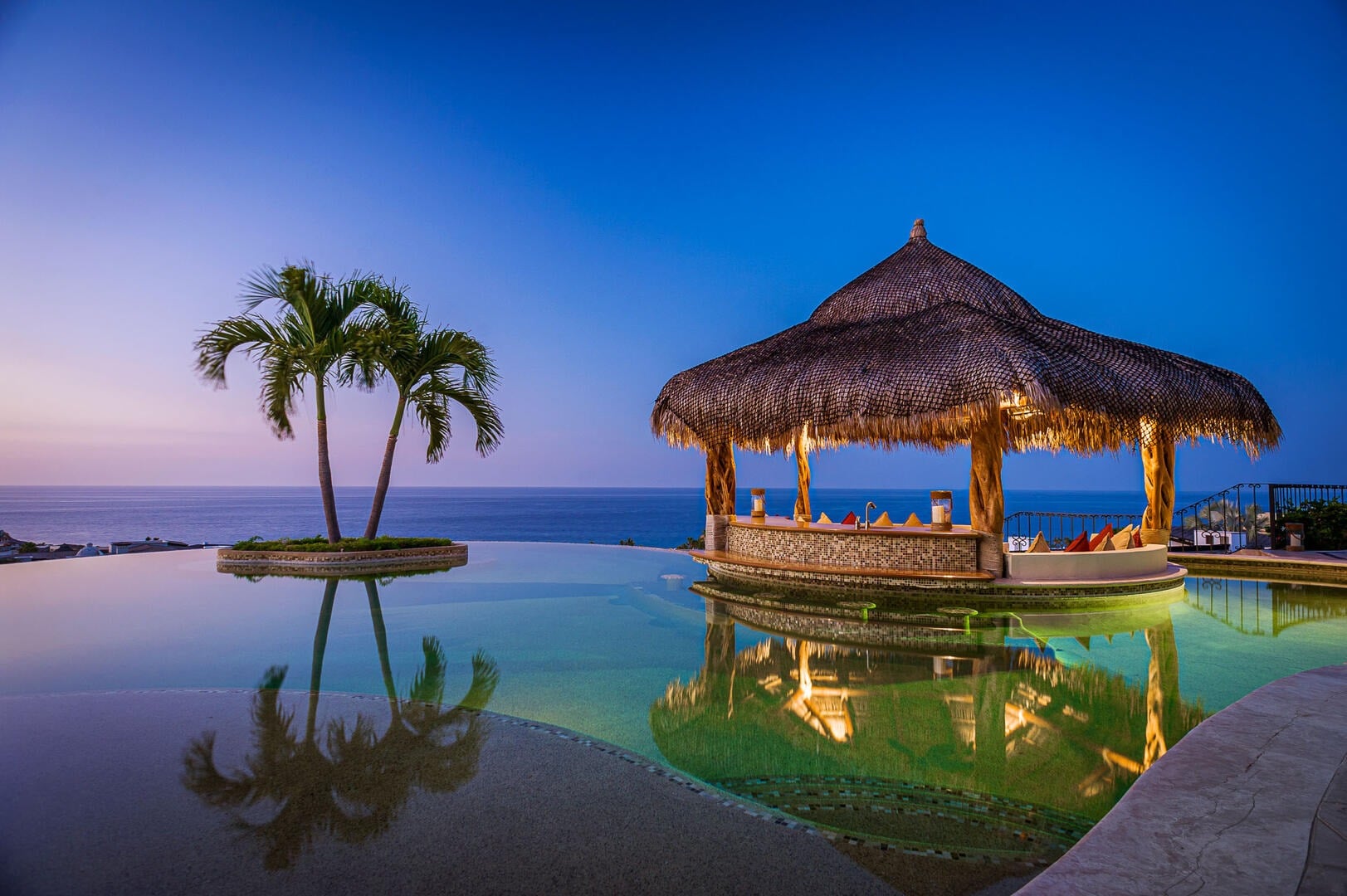 Villa Amistad thatched palapa bar and twin palms reflected in the pool at dusk — Punta Mita, Mexico