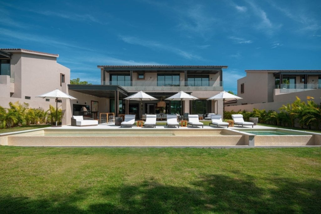 Villa Amistad from the lawn: white umbrellas and loungers along the pool and spa — Punta Mita, Mexico