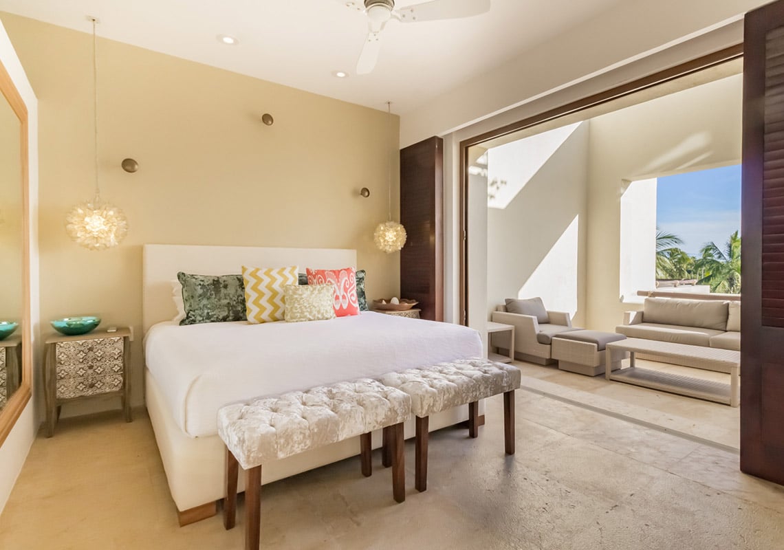 Condo Terrazas B32 bed with a bench at its foot below two woven pendant lights — Punta Mita, Mexico