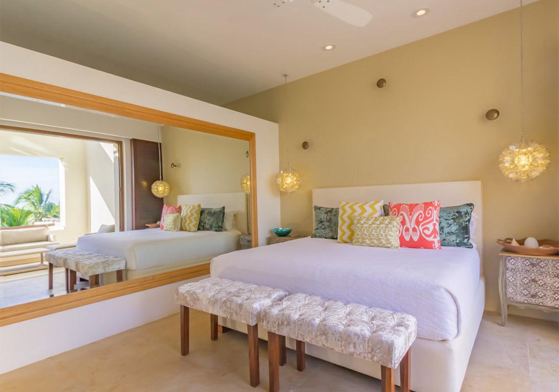 Condo Terrazas B32 the bed and its patterned cushions reflected in the mirrored wall — Punta Mita, Mexico