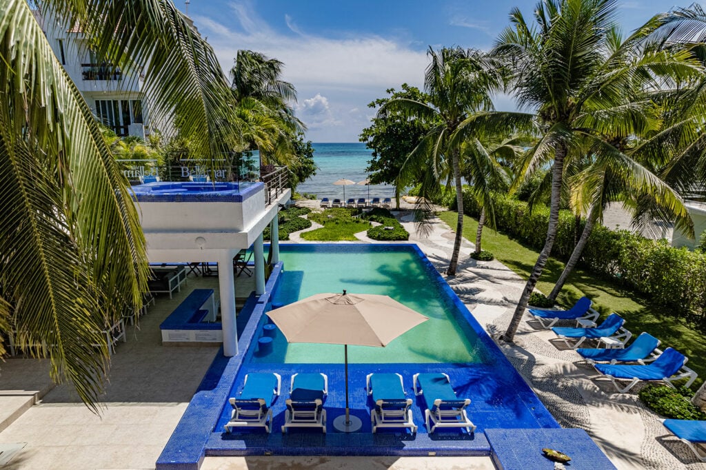 Villa Bellamar four blue loungers and an umbrella on a shallow pool ledge — Akumal, Mexico
