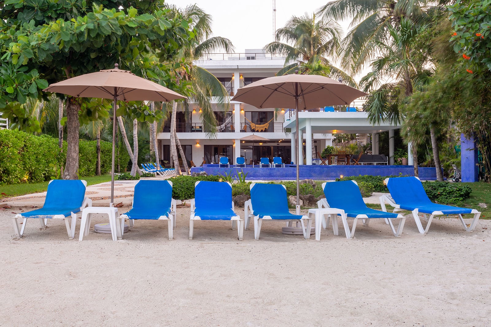 Villa Bellamar six blue loungers and two umbrellas on sand before the villa — Akumal, Mexico