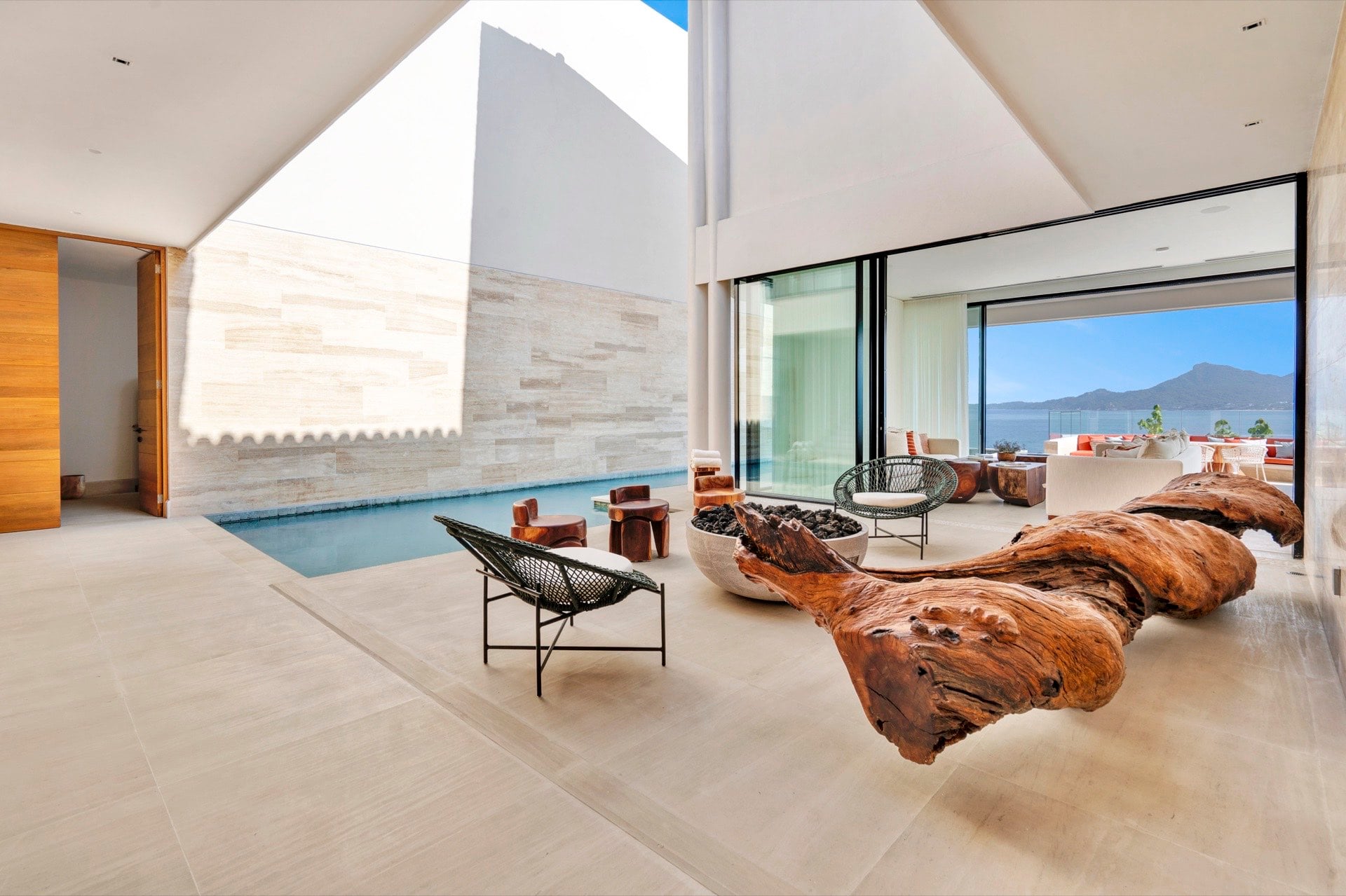 Casa Dinamita double-height lounge with sculptural wood pieces beside a narrow pool — Punta Mita Nayarit, Mexico