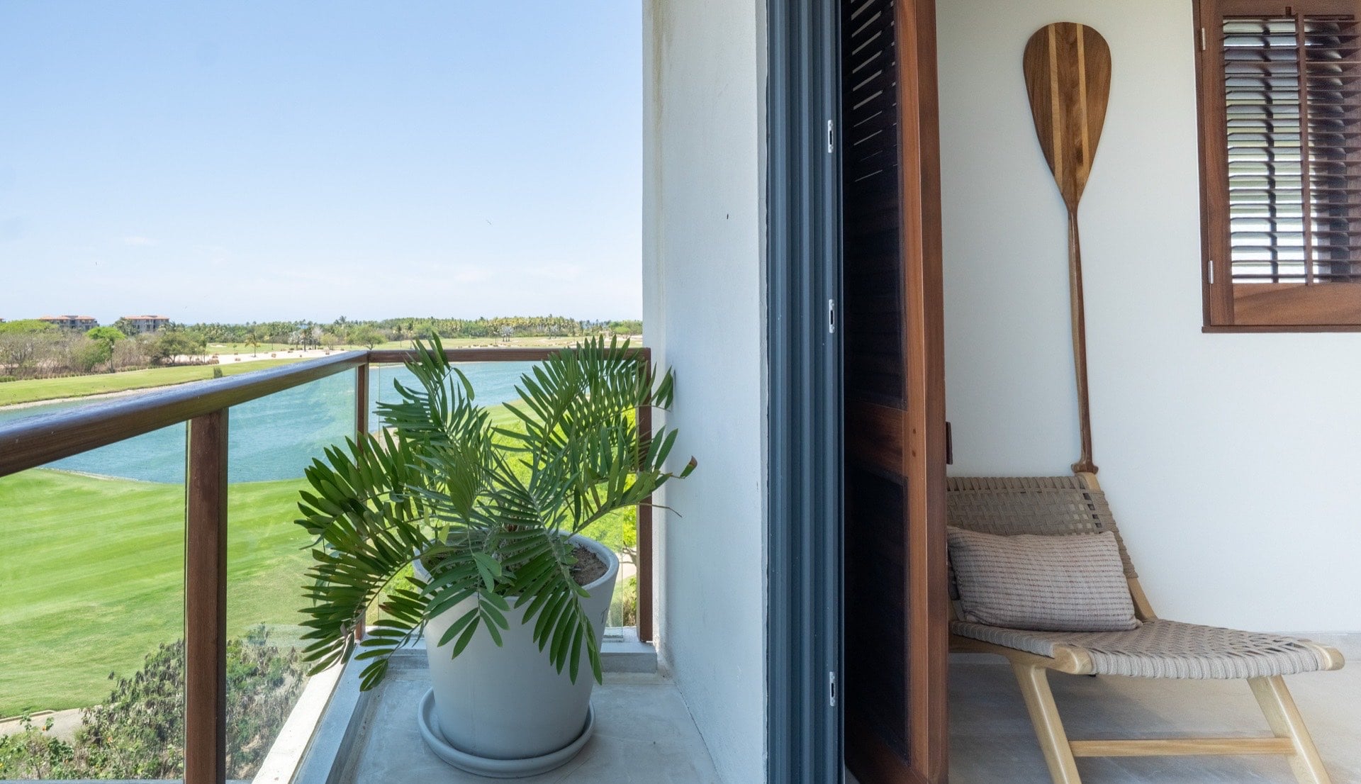 Condo El Encanto 1021 balcony corner with a potted palm, chair and golf view — Punta Mita Nayarit, Mexico