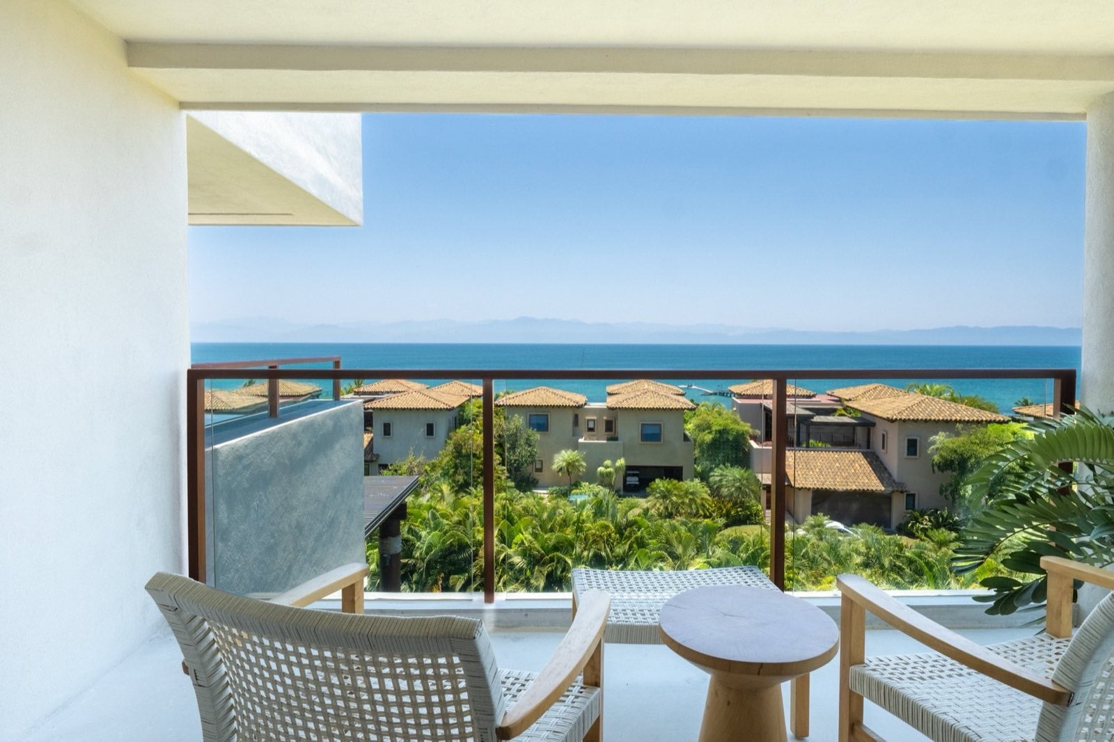 Condo El Encanto 1021 balcony with two chairs and a round table overlooking roofs and ocean — Punta Mita Nayarit, Mexico