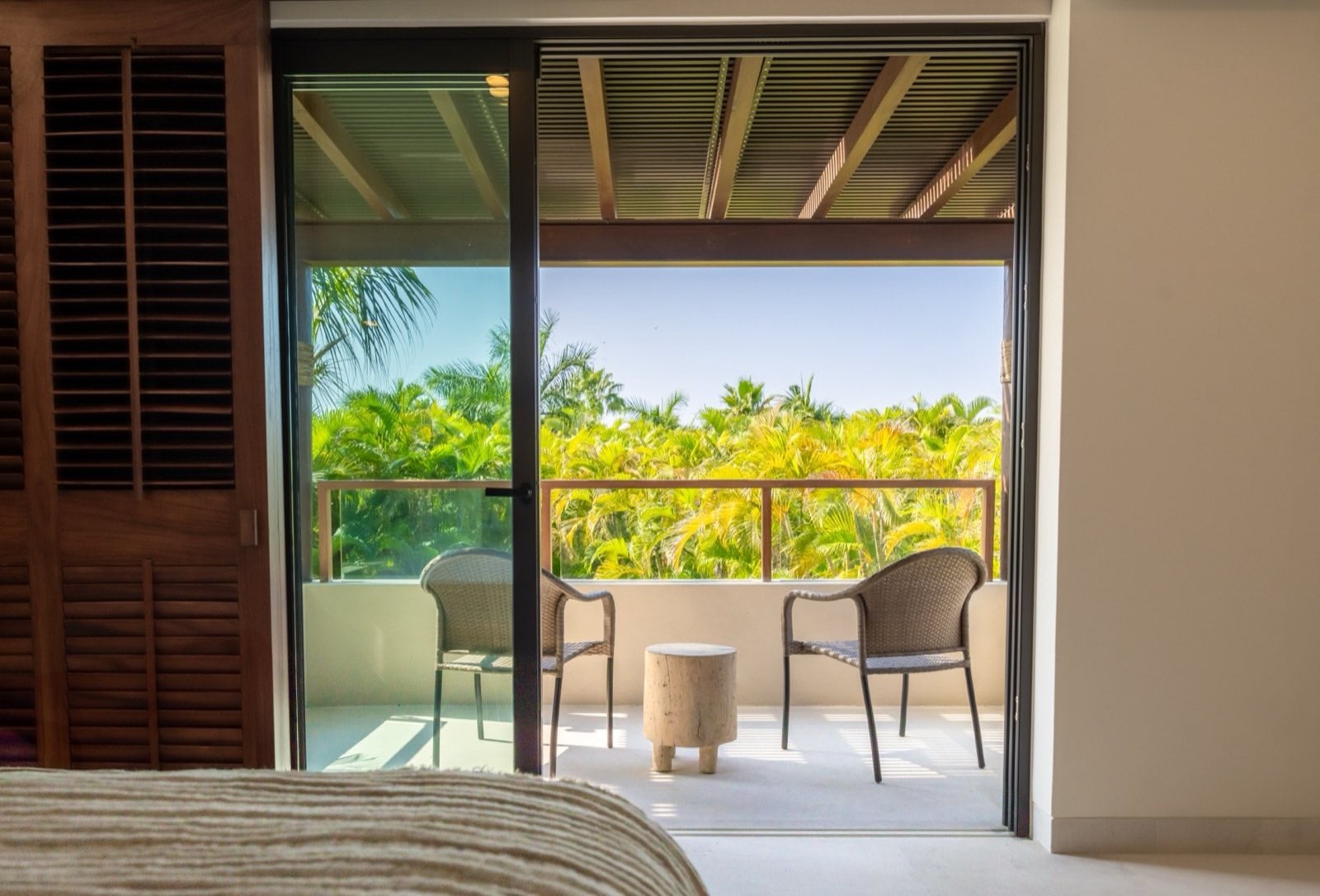 Condo El Encanto 401 bedroom doors opening to a balcony with two chairs and palms — Punta Mita Nayarit, Mexico