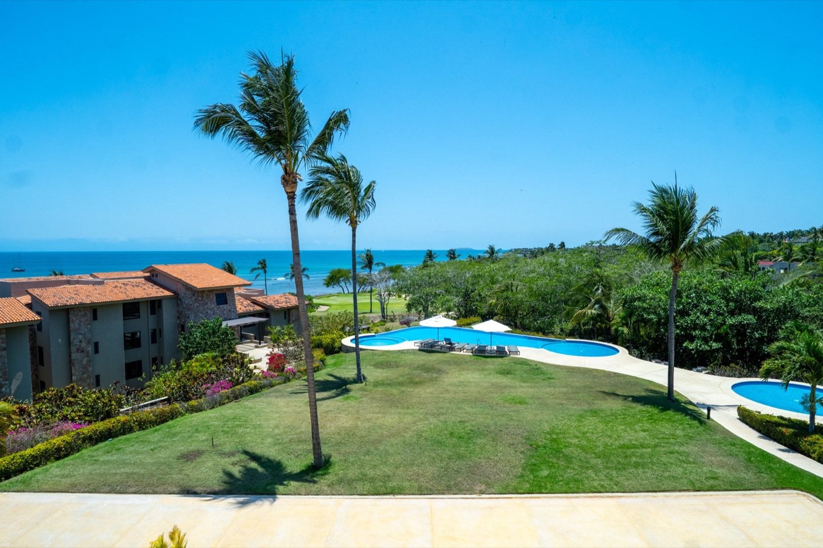 Condo Hacienda de Mita 705 elevated view over lawn, pools, palms, and ocean — Punta Mita Nayarit, Mexico