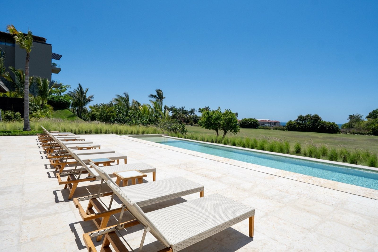 Condo Tau 131 row of white loungers beside a long lap pool and grassy grounds — Punta Mita Nayarit, Mexico