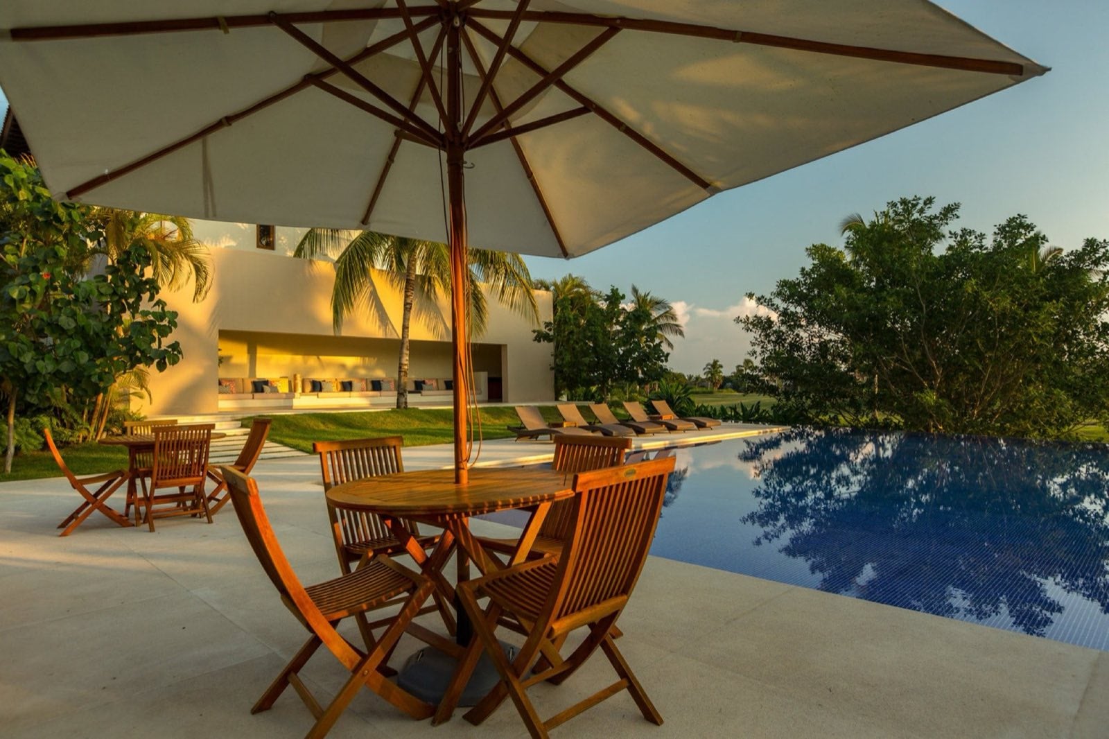 Condo Terazzas P23 poolside terrace with a white umbrella over a wood dining set — Punta Mita Nayarit, Mexico