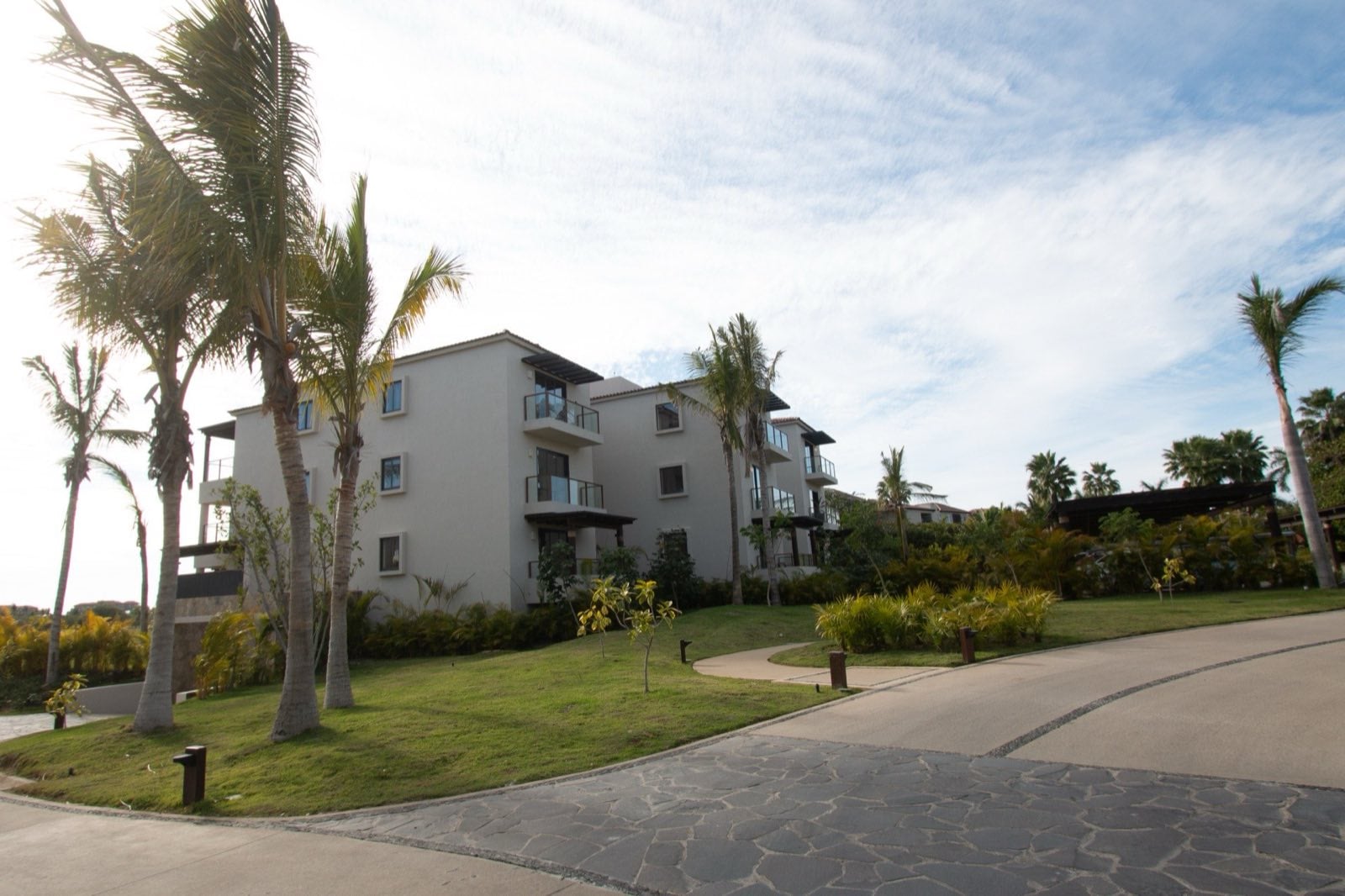 Condo El Encanto 821 exterior of the residence building with palms and paved driveway — Punta Mita Nayarit, Mexico