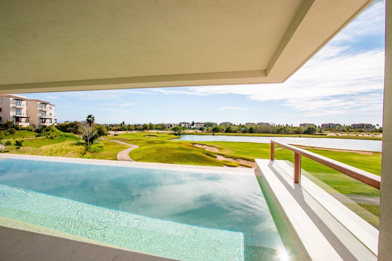 Condo El Encanto 821 pool edge overlooking a golf course and lake through a glass railing — Punta Mita Nayarit, Mexico