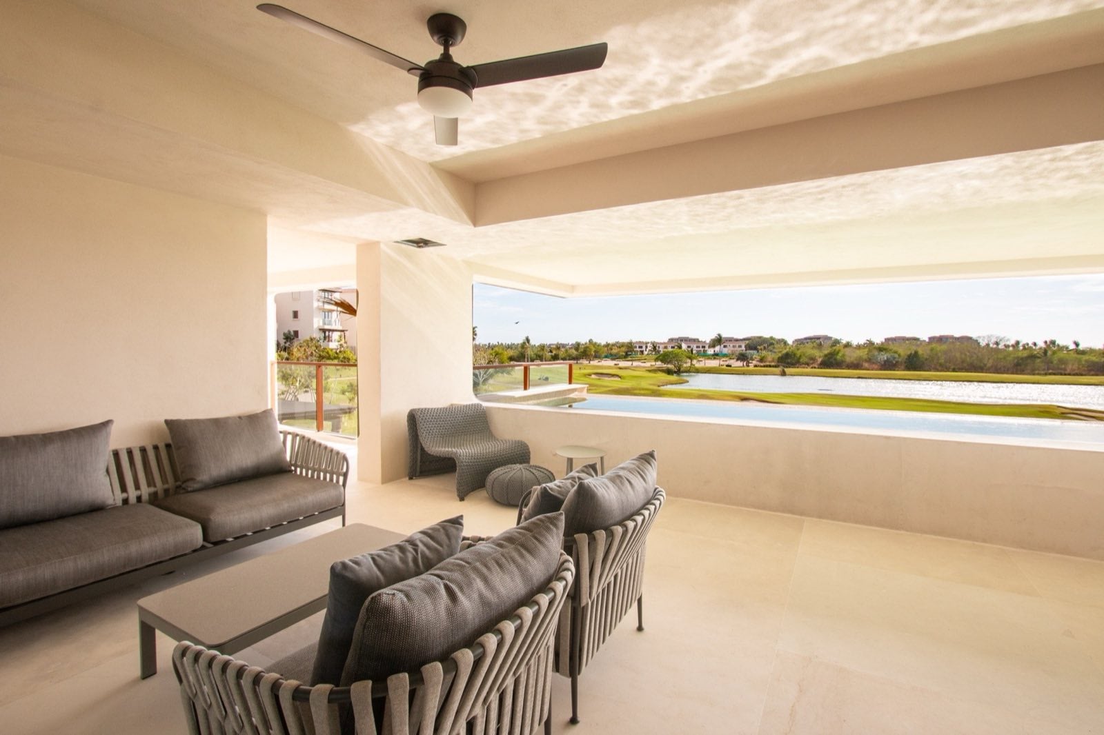 Condo El Encanto 821 covered terrace with gray lounge sofas, ceiling fan and golf view — Punta Mita Nayarit, Mexico