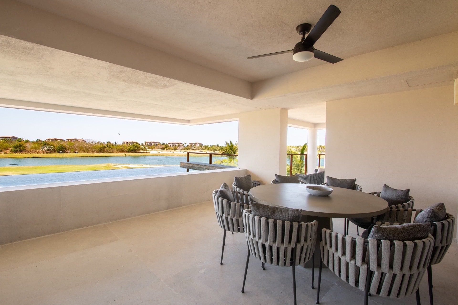 Condo El Encanto 821 covered terrace with round dining table, woven chairs and golf view — Punta Mita Nayarit, Mexico