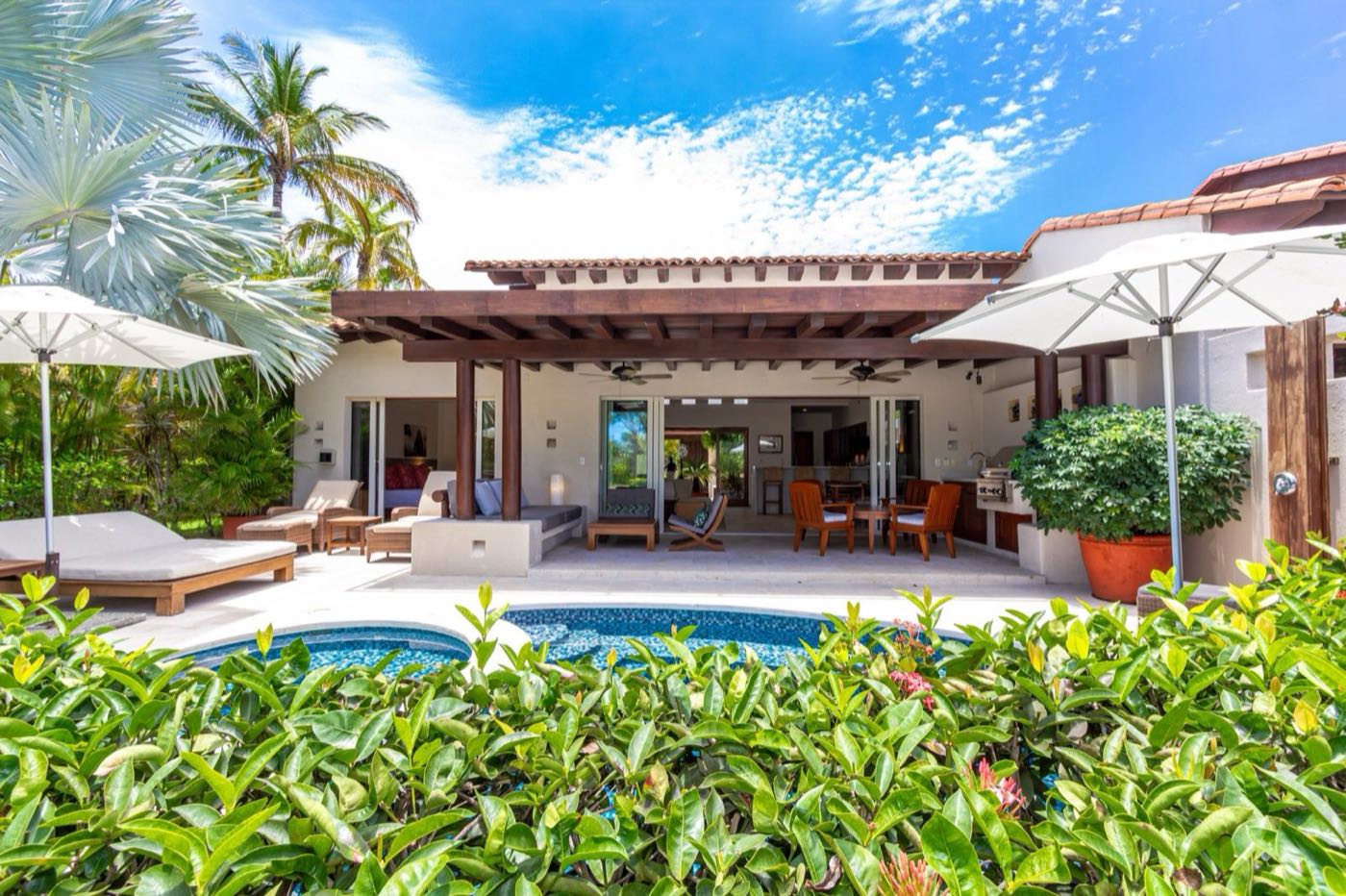Villa Cazadores pool and covered terrace framed by a garden hedge — Punta Mita Nayarit, Mexico