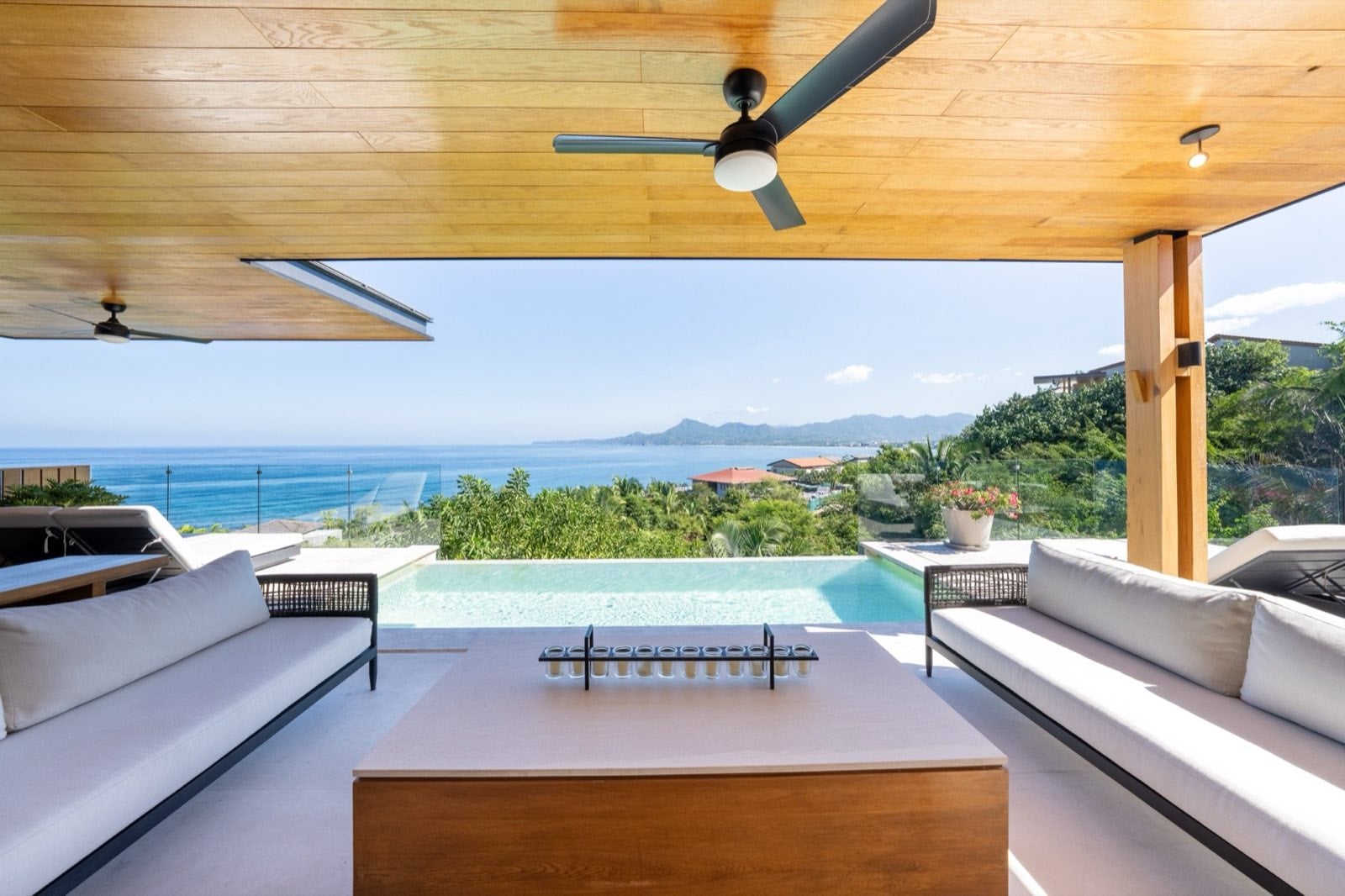 Villa La Vista covered lounge with facing sofas, pool, and ocean view — Punta Mita Nayarit, Mexico