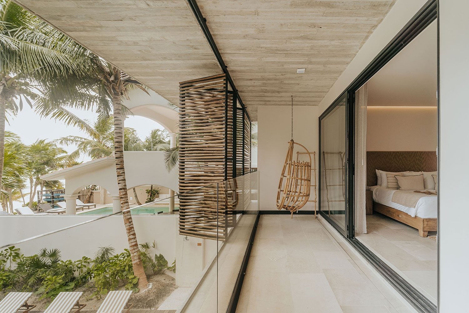 Azumaya Beach House upper balcony with rattan swing chair and pool view — Soliman Bay Tulum