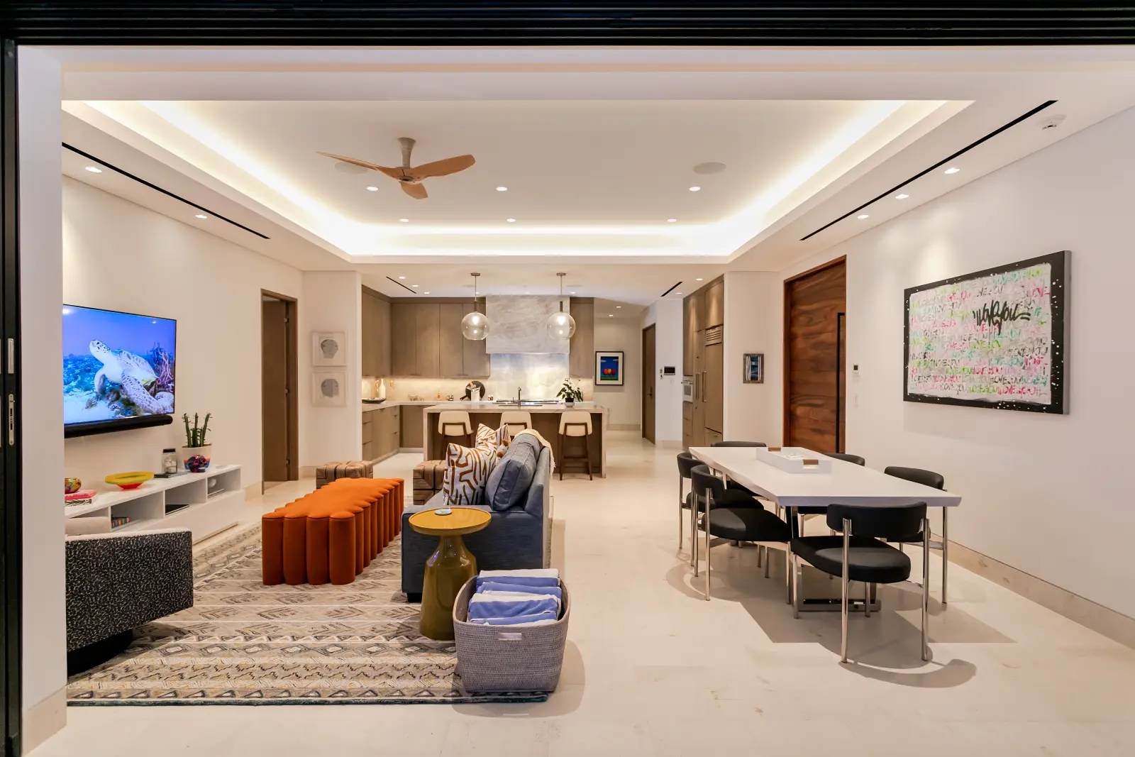 Bungalow 7 living room with a grey sofa, orange bench and the dining table beyond — Los Cabos, Mexico