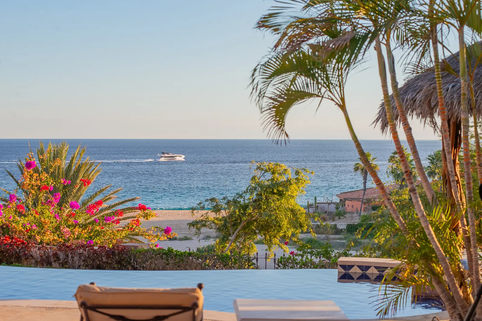 Casa Lolita a boat crossing the bay seen past bougainvillea from the pool — Los Cabos, Mexico