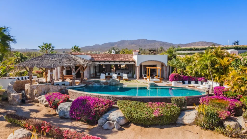 Casa Mar the curved pool and bougainvillea below the house and mountains — Los Cabos, Mexico
