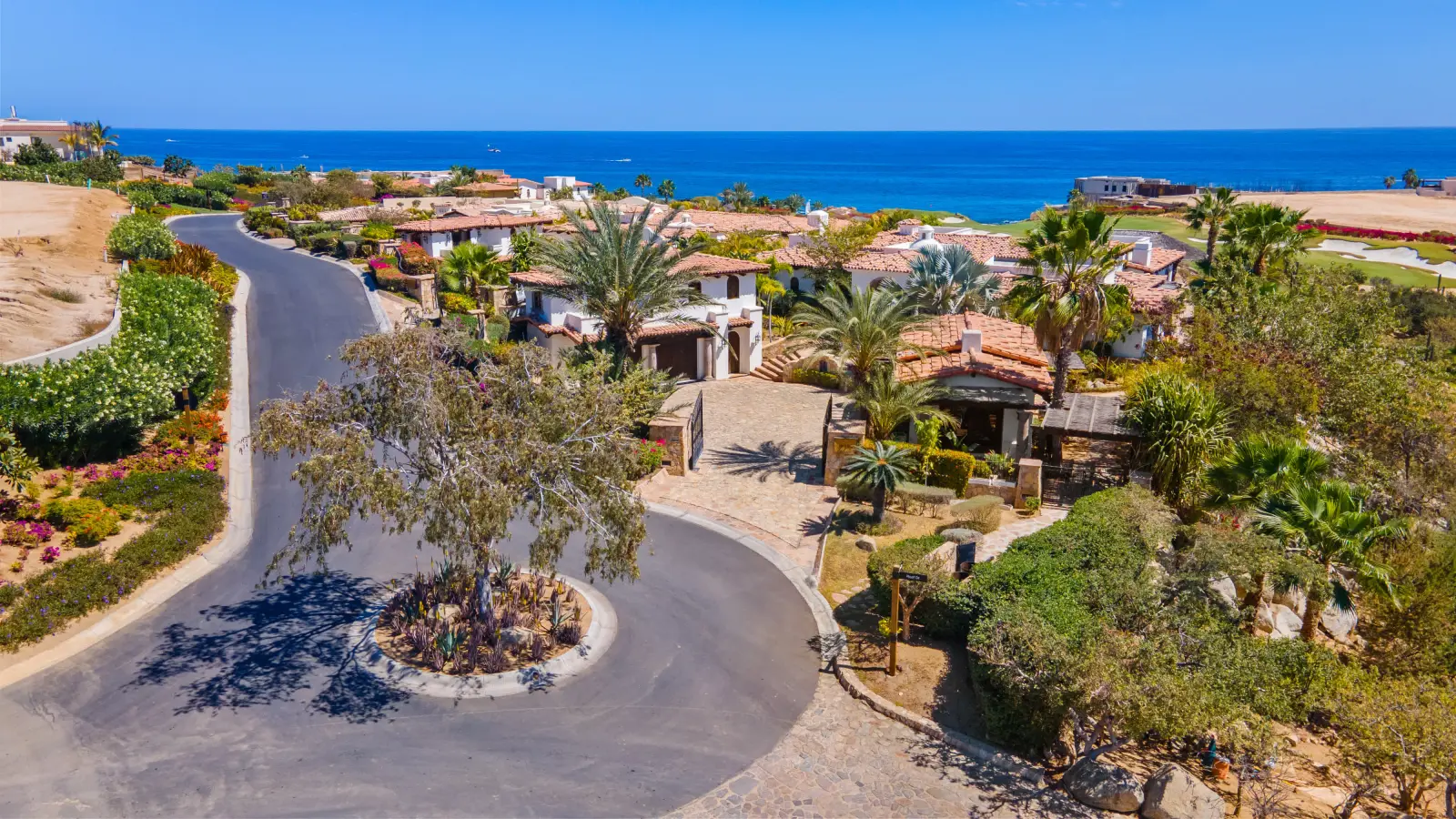 Casa Mar tiled roofs and palms along the curving street above the sea — Los Cabos, Mexico