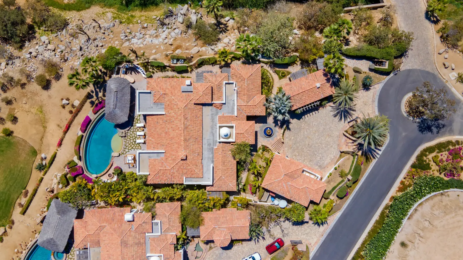 Casa Mar from directly above: tiled roofs around the pool and thatched palapa — Los Cabos, Mexico