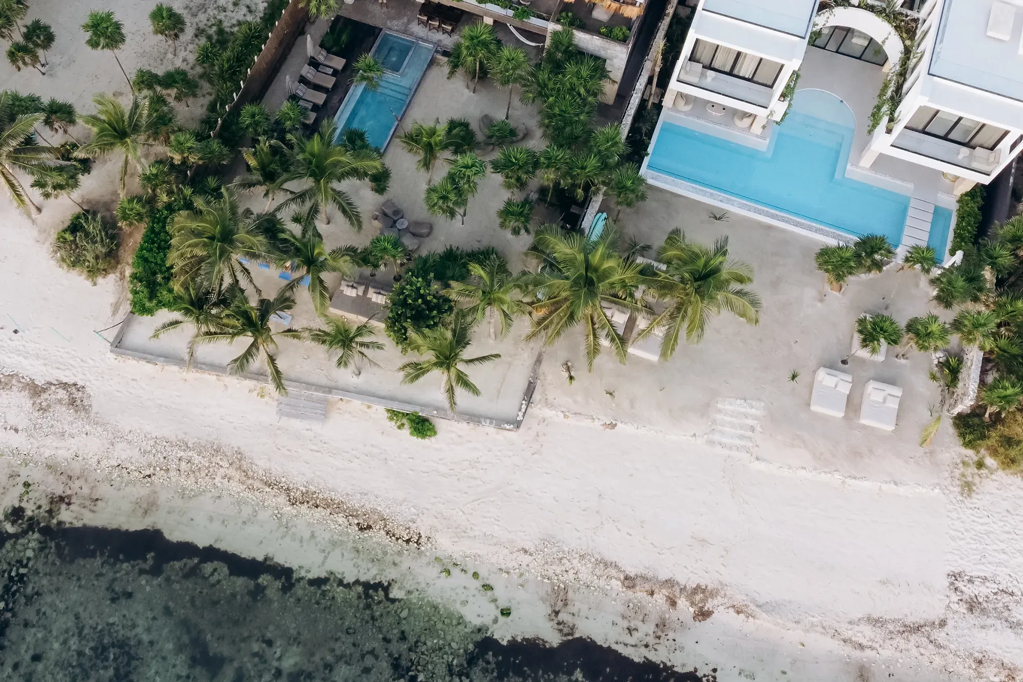 Studio 54 overhead aerial of the white villa, pools and sandy shoreline — Tulum, Mexico
