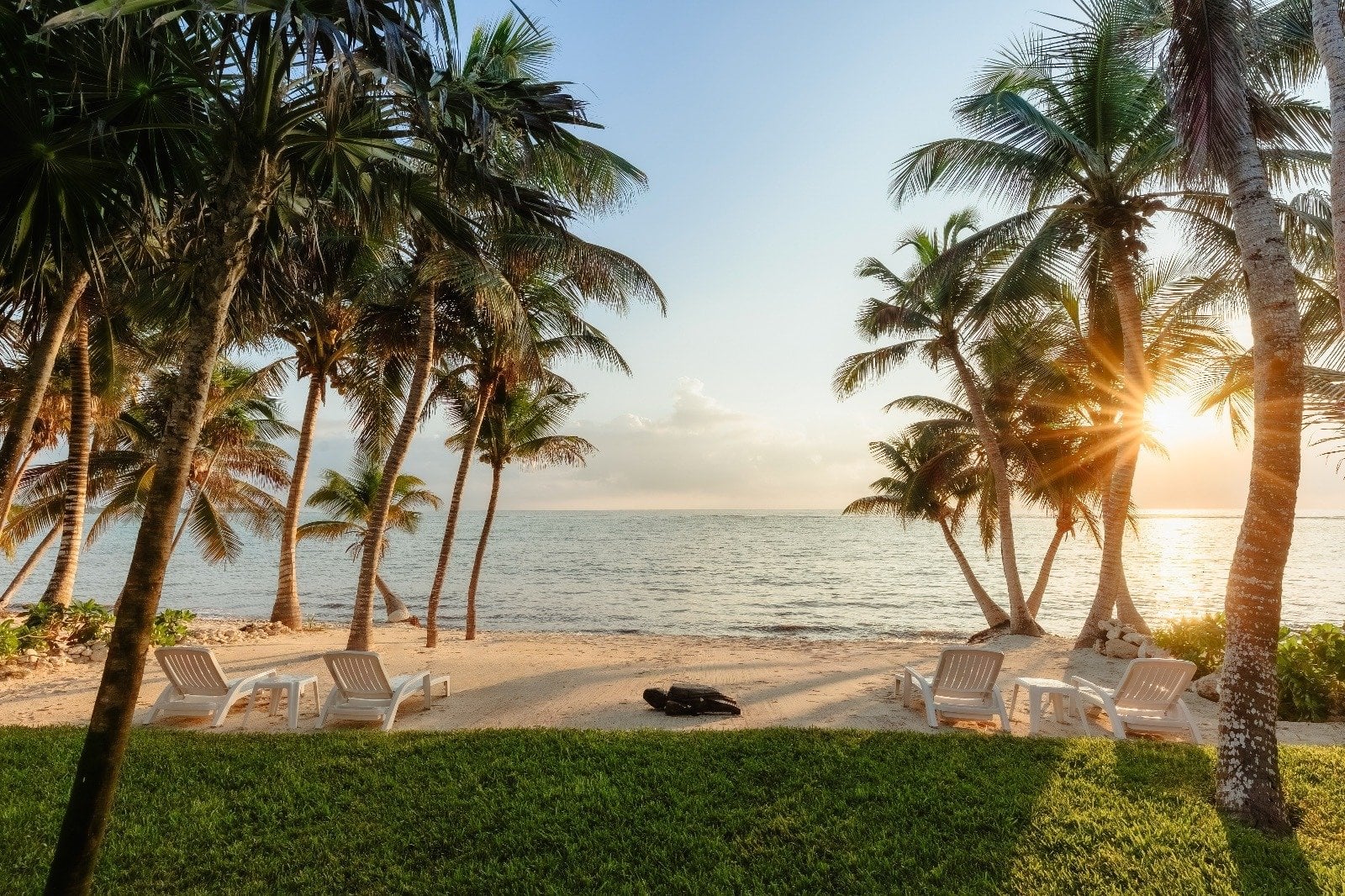 Villa Dulce Vida sunset over a sandy beach with palm trees and white loungers — Riviera Maya, Mexico