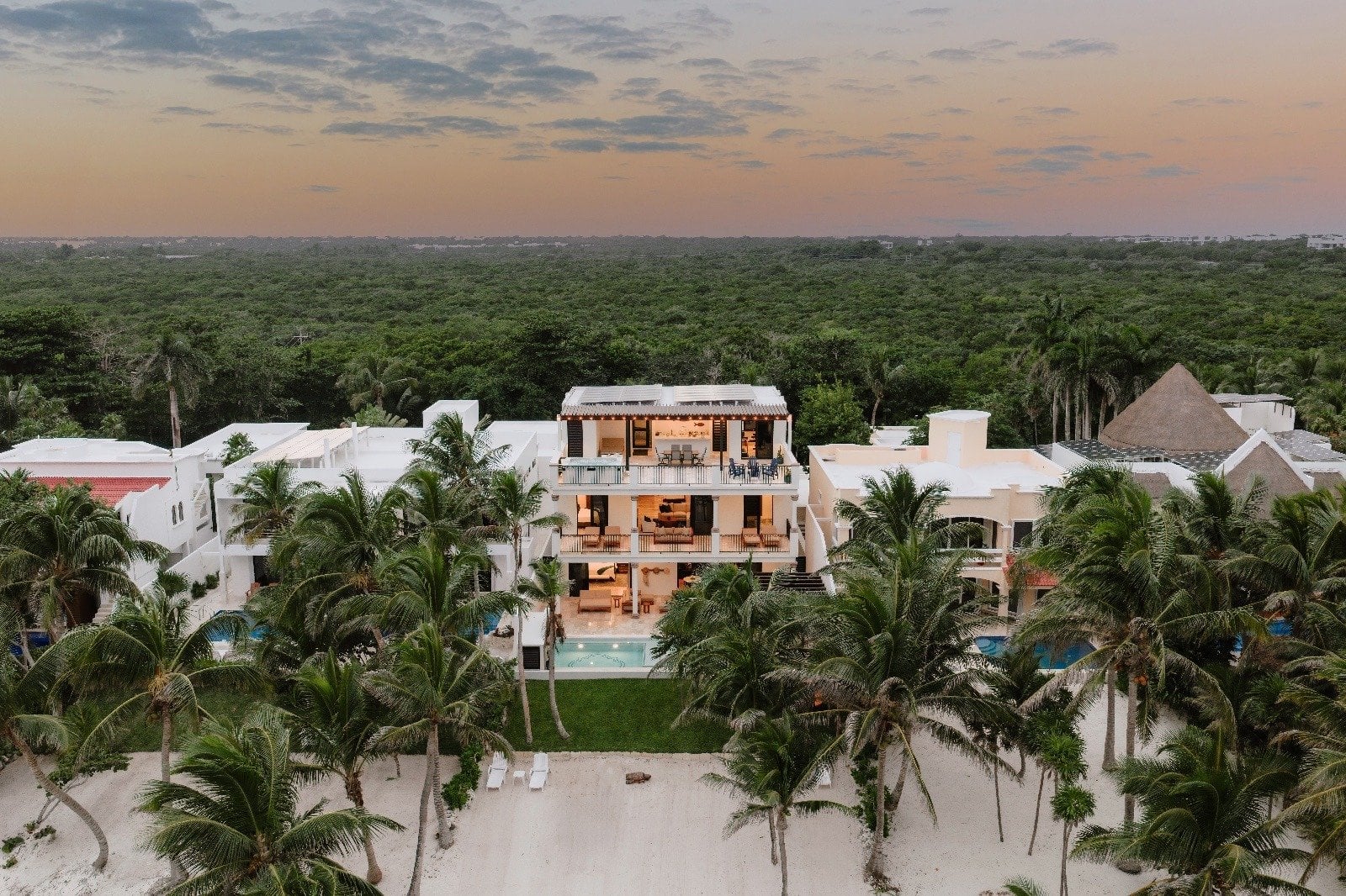 Villa Dulce Vida wide aerial view between a palm-lined beach and forest at dusk — Riviera Maya, Mexico