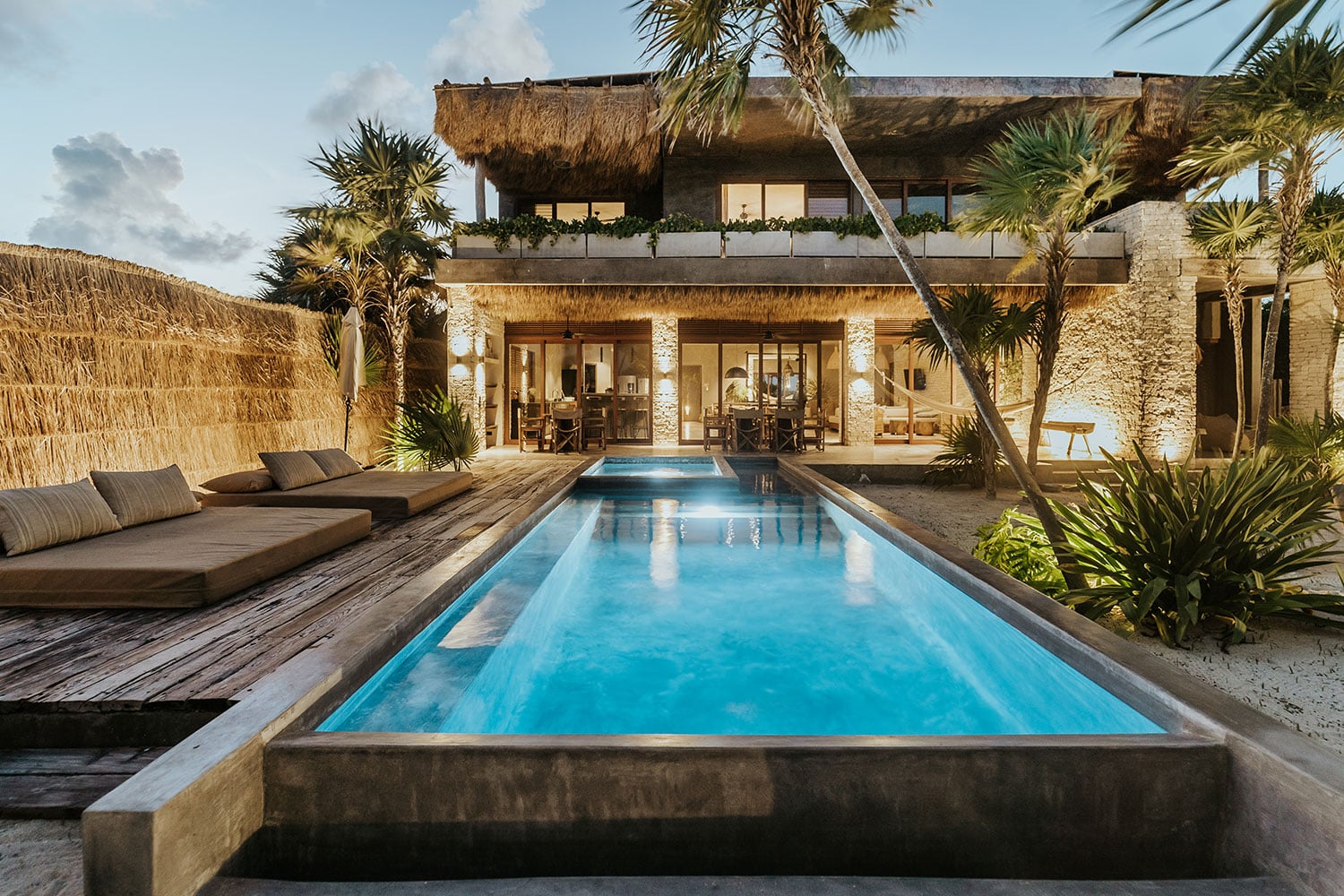 Villa Moloch illuminated lap pool with wooden deck daybed at twilight — Soliman Bay Tulum