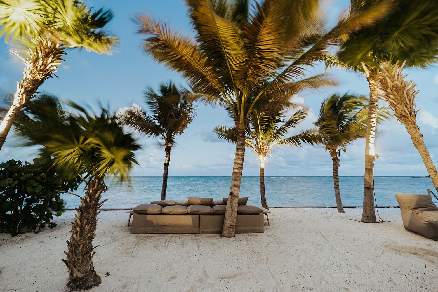 Villa Moloch beachfront outdoor lounge sofa beneath swaying coconut palms — Soliman Bay Tulum