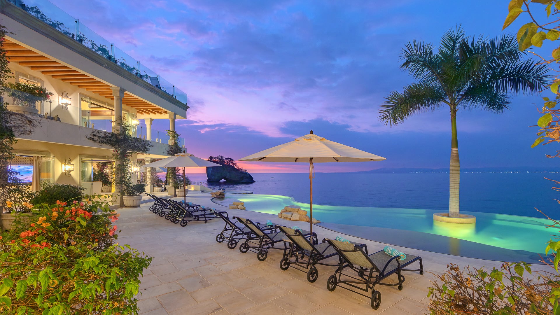 Casa Michael pool terrace, palms, and offshore rock at sunset — Puerto Vallarta, Mexico
