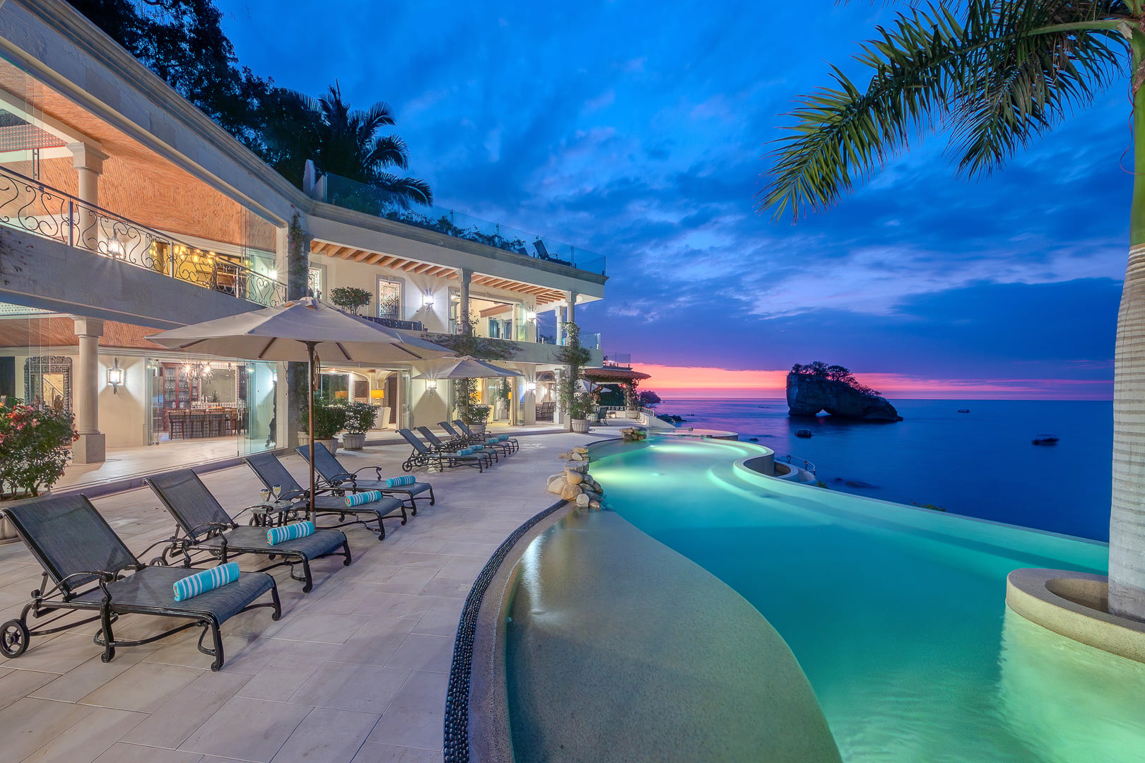 Casa Michael illuminated pool and row of loungers at blue hour — Puerto Vallarta, Mexico