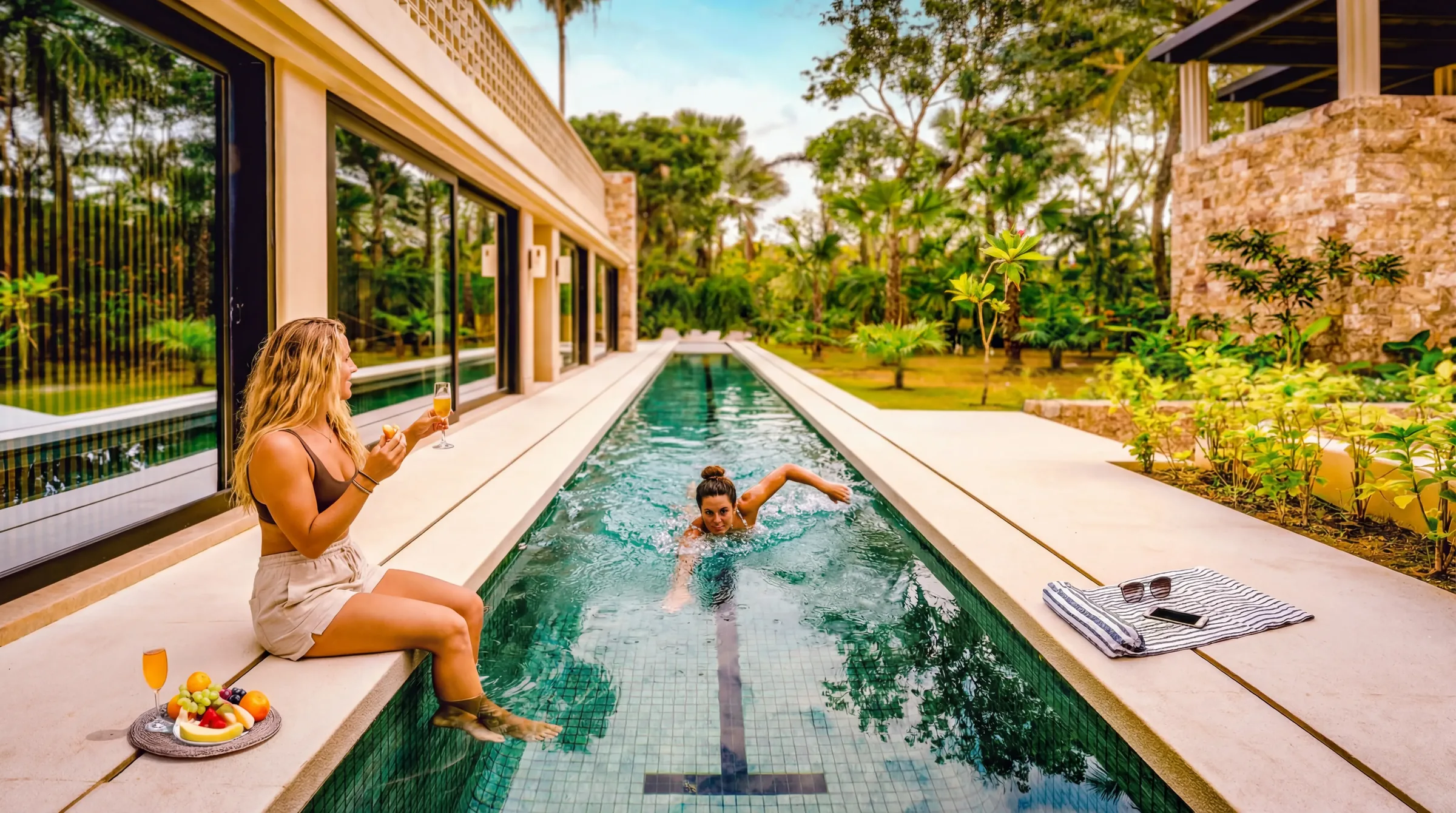 Casa Happy Paws woman seated beside a swimmer in the narrow garden pool — Punta Mita Nayarit, Mexico