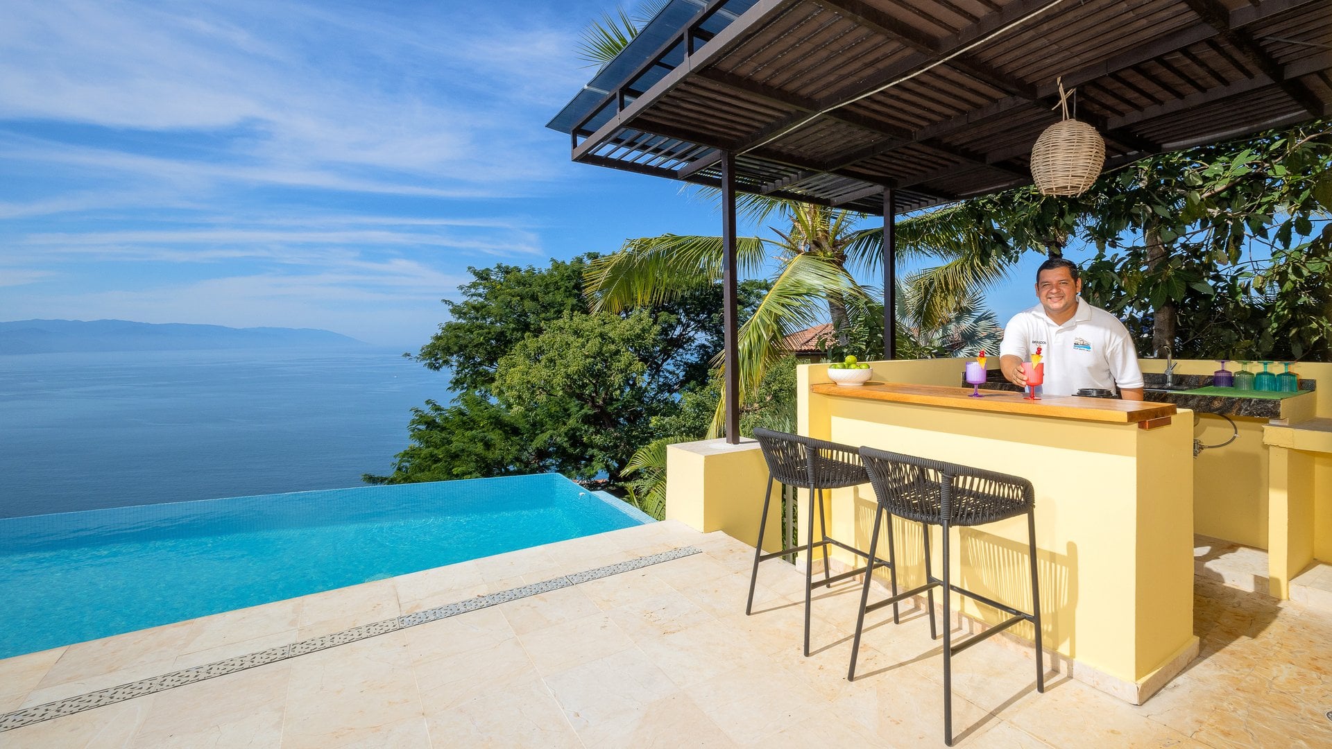 Villa Santa Cruz pool terrace with a bar, three stools and an ocean view — Puerto Vallarta, Mexico