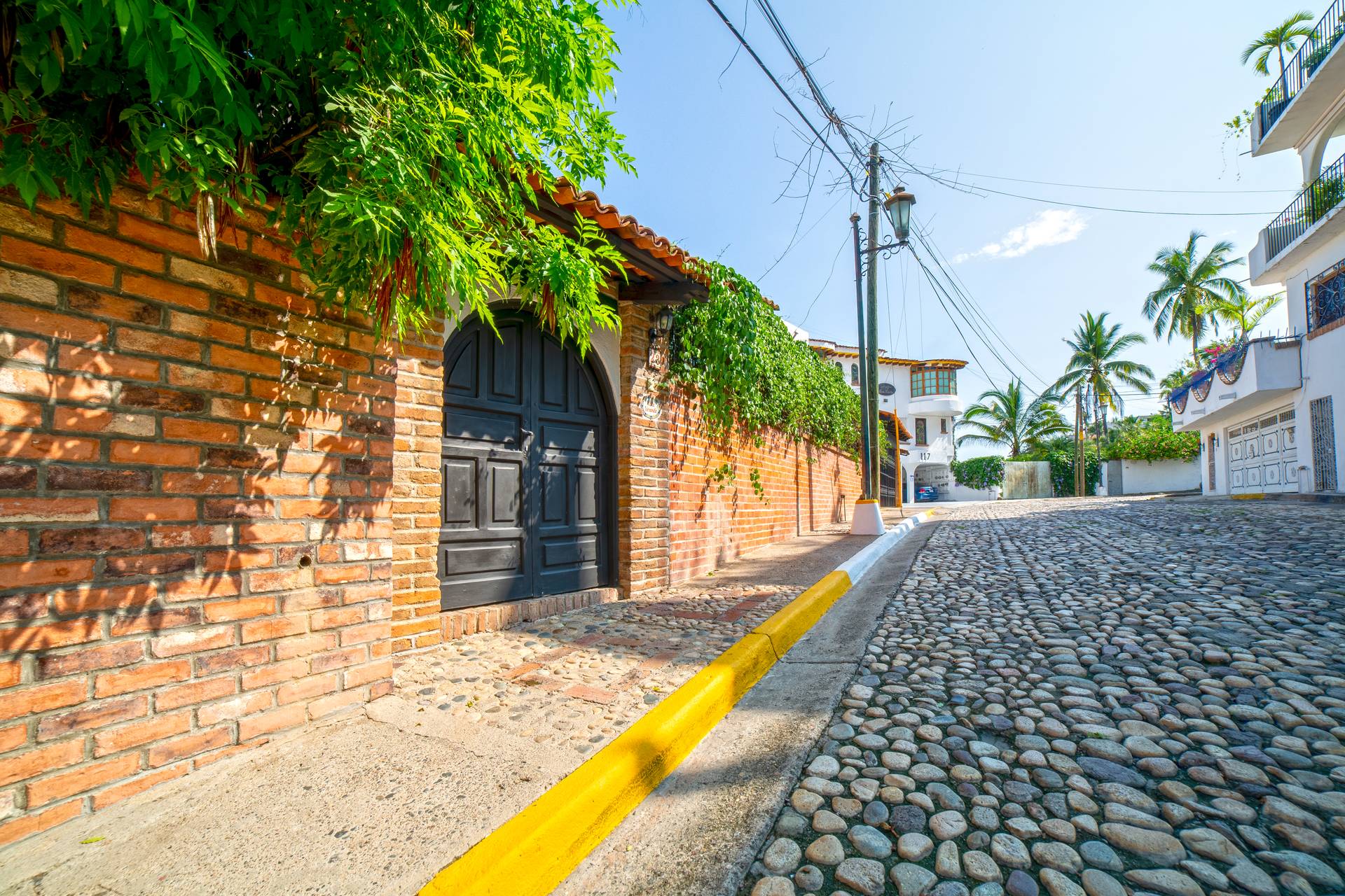 Villa Veranda cobblestone street beside a brick wall and black door — Puerto Vallarta, Mexico
