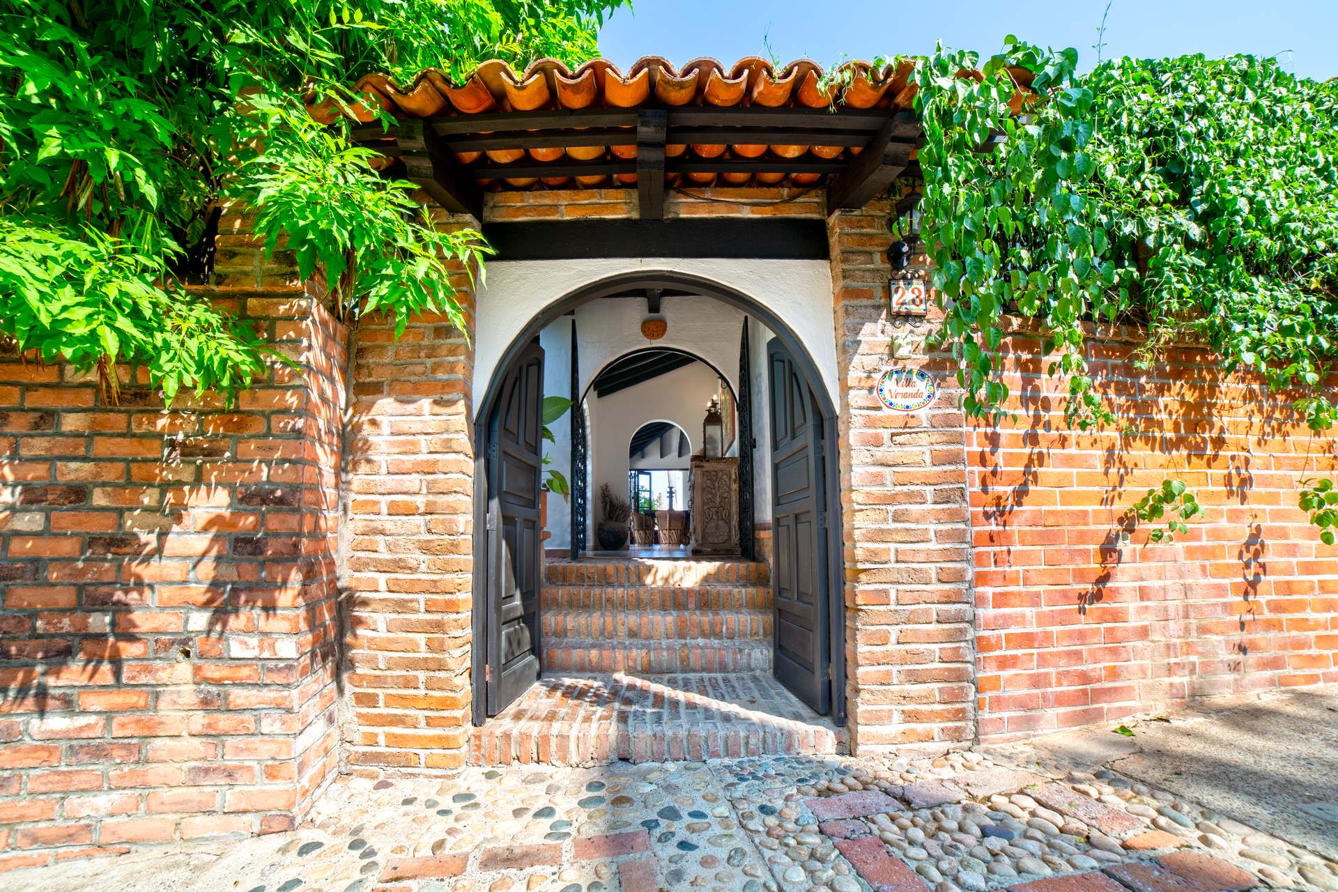 Villa Veranda open arched gate set into an ivy-covered brick wall — Puerto Vallarta, Mexico